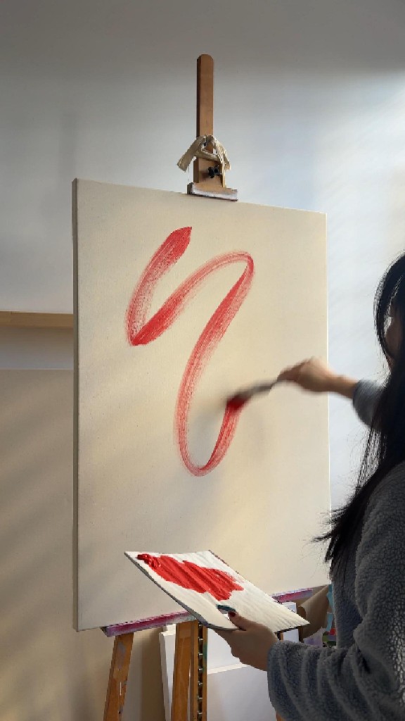 Painting a red form on canvas in the studio
